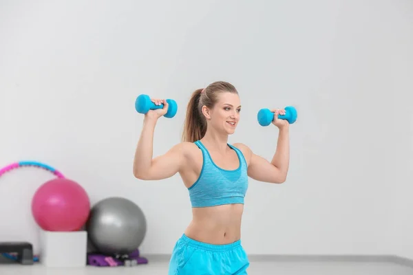 Ung sportig kvinna träning med hantlar i gymmet — Stockfoto