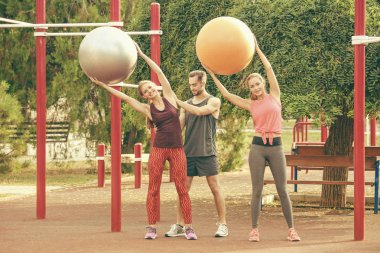 Genç kadın fitness topu parkta eğitmen gözetiminde eğitim