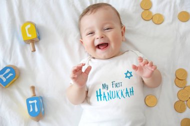 Şirin Bebek sevinçler ve yatakta yatarken para ile. İlk Hanukkah kutlama kavramı