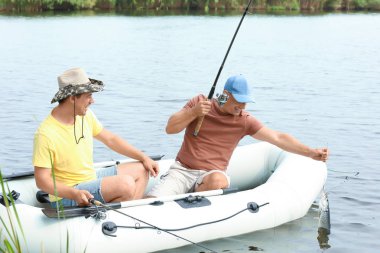 İki adam Nehri üzerinde şişme tekneden Balık tutma