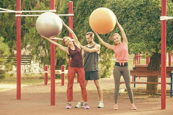 Young women training with fitness balls under trainer supervision in park — Stock Photo, Image
