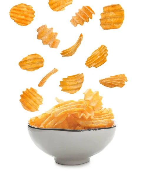 Tasty potato chips falling into bowl — Stock Photo, Image