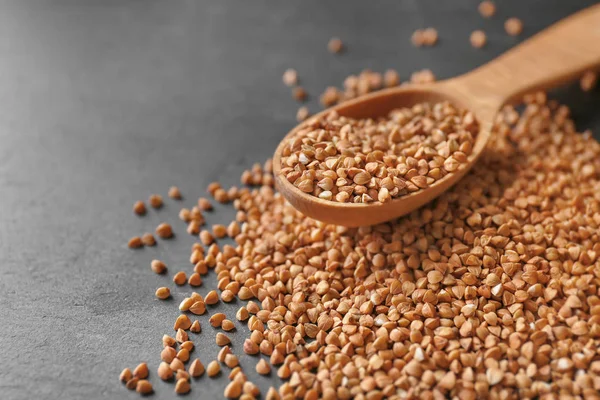 Raw buckwheat and wooden spoon — Stock Photo, Image