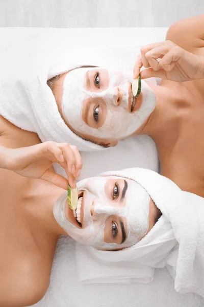 Young women with facial masks and cucumber slices in spa salon — Stock Photo, Image