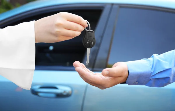 Saleswoman giving car key to customer outdoors — Stock fotografie