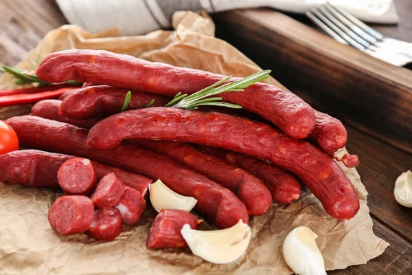 Delicious smoked sausages on parchment — Stock Photo, Image