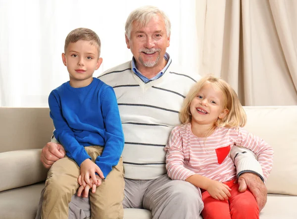 Пожилой человек с внуками дома — стоковое фото
