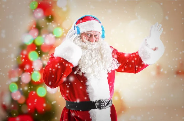 Weihnachtsmann mit Kopfhörern, die Weihnachtsmusik hören und Schnee-Effekt auf verschwommenem Hintergrund — Stockfoto