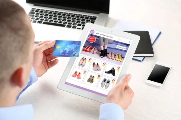 Man met behulp van Tablet PC- en creditcard voor online winkelen van internet aan tafel — Stockfoto