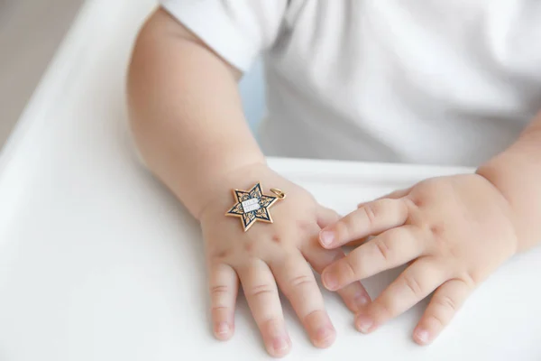 Star of David pendant on hand of baby, closeup
