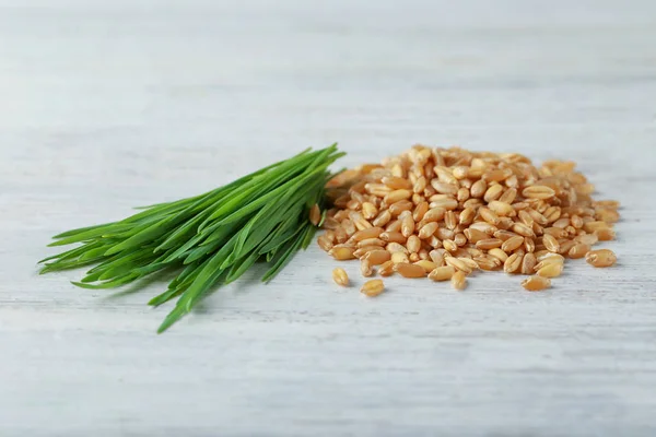 Pile of seeds and wheat grass on wooden table — Stock Photo, Image