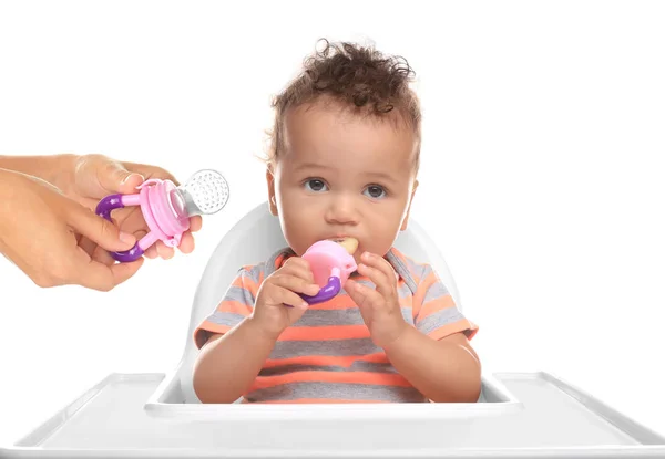 Baby zit in kinderstoel en vrouwelijke handen met nibbler op witte achtergrond — Stockfoto