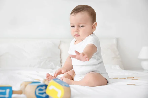 Niedliches Baby spielt mit Dreidels im Bett — Stockfoto