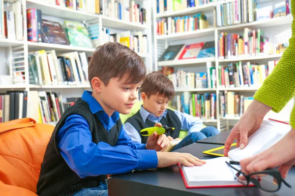 Professor e crianças na biblioteca da escola — Fotografia de Stock