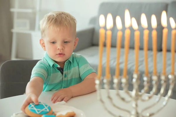 Joodse jongen eten feestelijke Hanukkah cookies thuis — Stockfoto