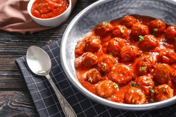 Кастрюля с вкусными фрикадельками в томатном соусе на столе — стоковое фото