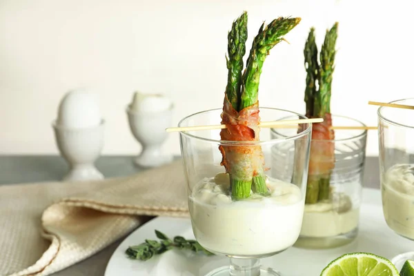 Bicchieri con bacon avvolto asparagi e salsa in tavola — Foto Stock