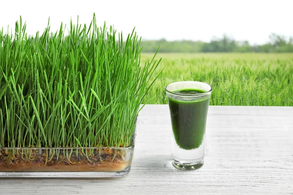 Verre de jus et champ d'herbe de blé — Photo