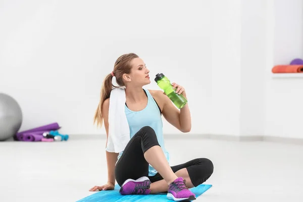 Mujer joven deportiva con botella de agua en el gimnasio —  Fotos de Stock