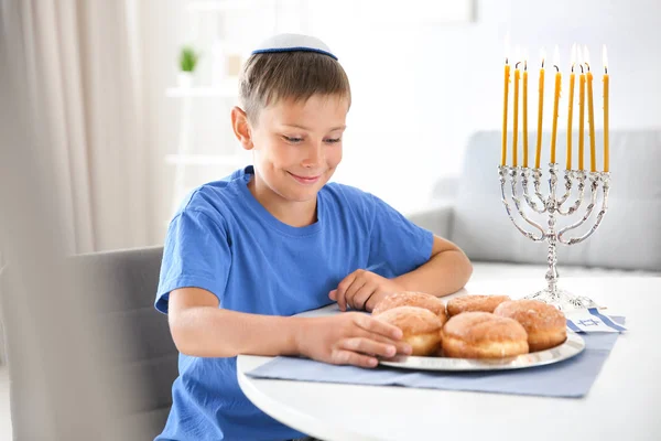 Joodse jongen met traditionele sufganiyah thuis — Stockfoto