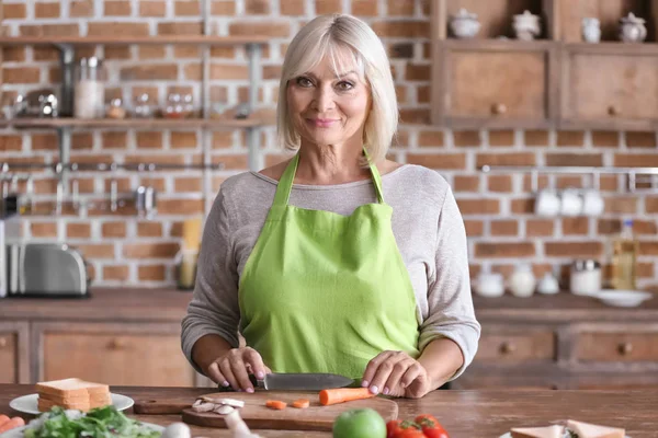 Mature woman cooking in kitchen — Stock Photo, Image