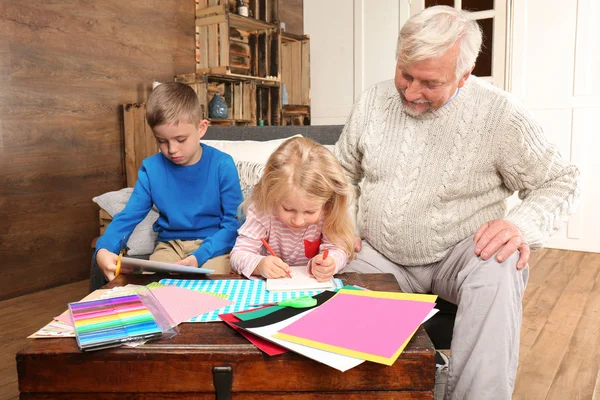 Oudere man met kleinkinderen thuis — Stockfoto