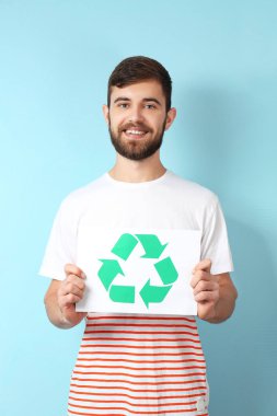 Genç adam ile renk arka plan üzerinde sembol geri dönüşüm kağıt levha holding