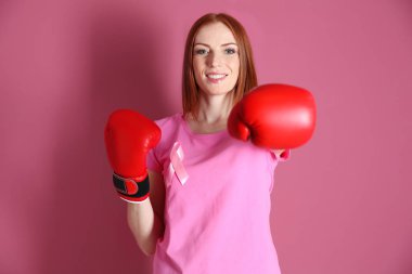 Pembe tişört ve boks eldivenleri renk arka plan üzerinde bir genç kadın. Meme Kanseri Bilinçlendirme kavramı