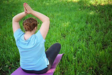 Kilolu kadınla çimenlerin üzerinde eğitim