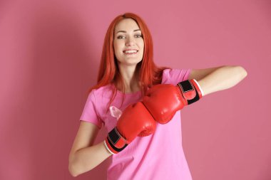 Pembe tişört ve boks eldivenleri renk arka plan üzerinde bir genç kadın. Meme Kanseri Bilinçlendirme kavramı