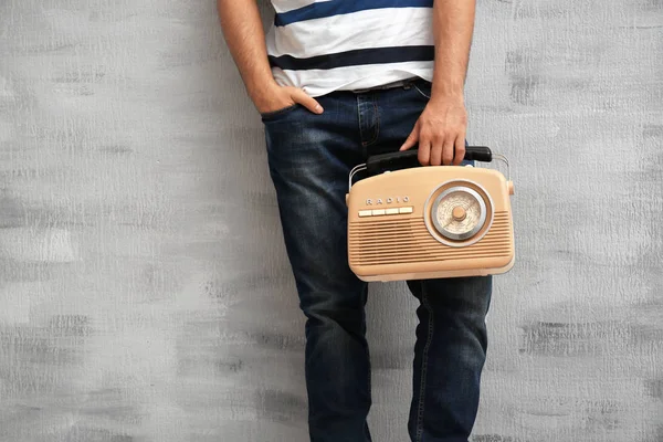 Young man holding retro radio on grey background