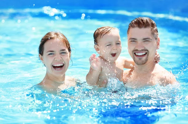 Gyermek medence leckét. Aranyos kisfiú tanulás úszni a medencében a szülők — Stock Fotó