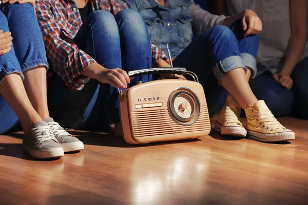 Group of young women with retro radio indoors