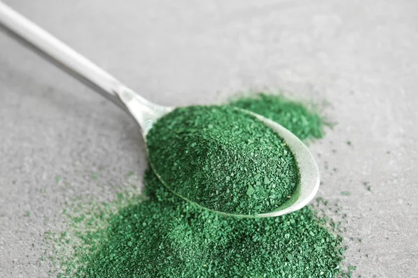 Lžíce s spirulina prášek na stole — Stock fotografie