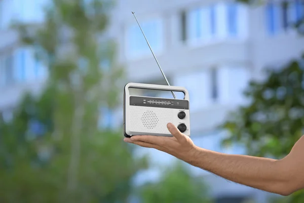 Young man with retro radio on blurred background