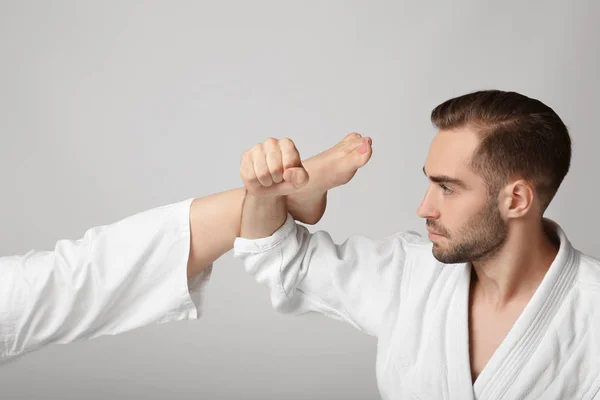 Joven en karategi bloqueando patada sobre fondo claro — Foto de Stock