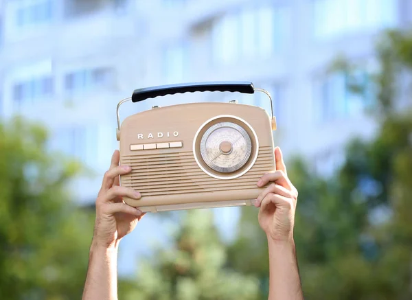 Young man with retro radio on blurred background