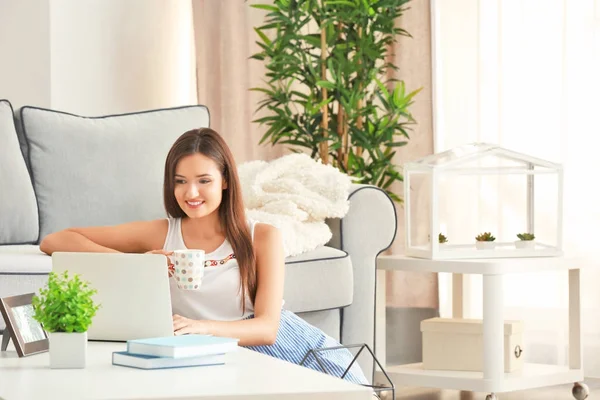 Ładna kobieta z nowoczesny laptop i kawę siedząc na podłodze w domu — Zdjęcie stockowe