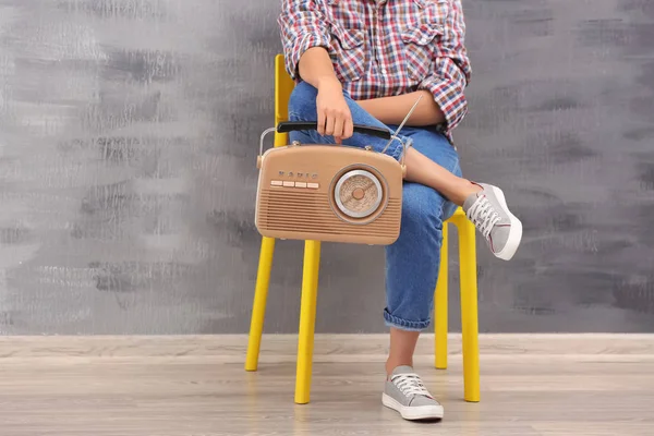 Jovem mulher com rádio retro sentado na cadeira dentro de casa — Fotografia de Stock