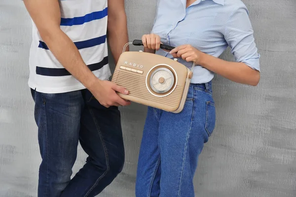 Jovem com mulher segurando rádio retro perto da parede cinza — Fotografia de Stock