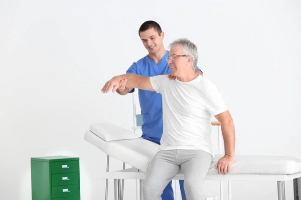 Fisioterapeuta trabajando con un paciente mayor en una clínica moderna — Foto de Stock