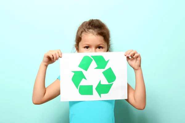 Niña sosteniendo hoja de papel con símbolo de reciclaje en el fondo de color — Foto de Stock