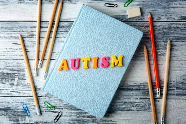 Word AUTISM fatto di lettere e blocco note su sfondo di legno — Foto Stock