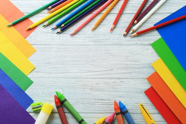 Цветные листы с карандашами для детского сада на деревянном фоне — стоковое фото