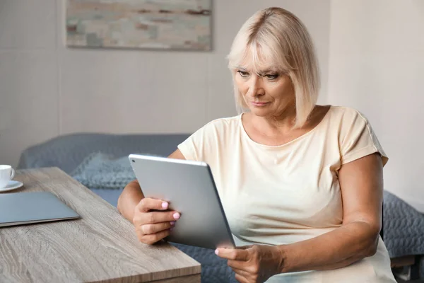 Mulher madura usando tablet em casa — Fotografia de Stock