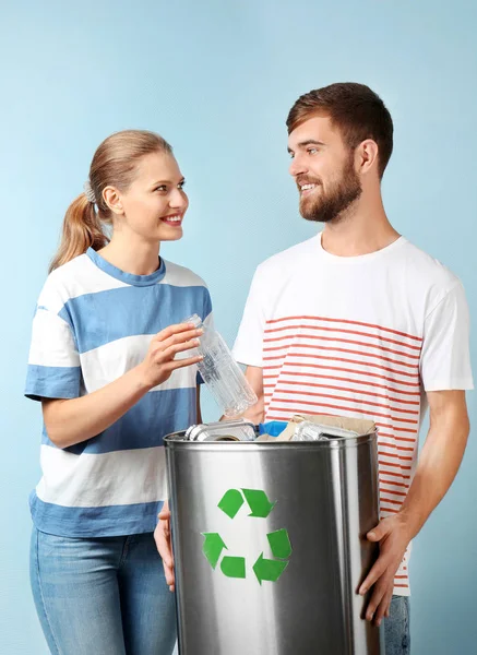 Pareja joven con papelera sobre fondo de color. Concepto de reciclaje —  Fotos de Stock