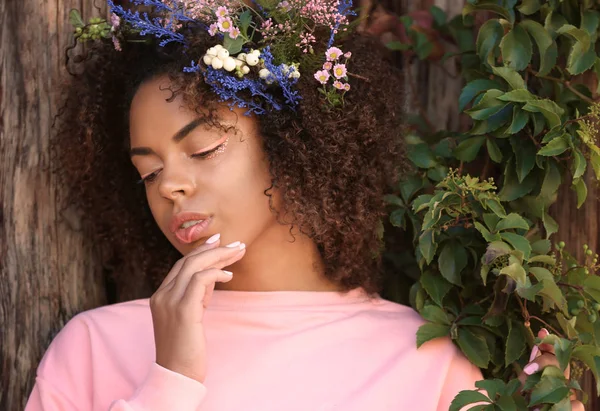 Vackra unga afroamerikanska kvinna med blommor utomhus — Stockfoto