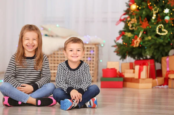 Lindos niños pequeños sentados en el suelo en la habitación decorada para Navidad — Foto de Stock