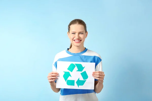 Jovem segurando folha de papel com símbolo de reciclagem no fundo de cor — Fotografia de Stock