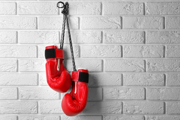 Paire de gants de boxe rouge suspendus au mur de briques — Photo